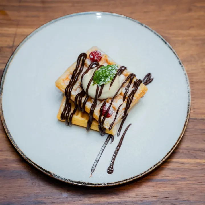 A sweet dessert plate with cream, berries and chocolate drizzle at Dear Breakfast