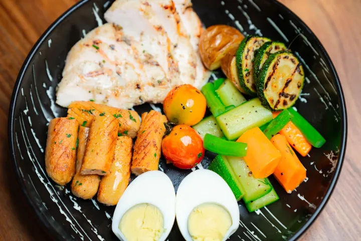 High-protein breakfast plate with grilled chicken, sausages, boiled egg and vegetables at Dear Breakfast